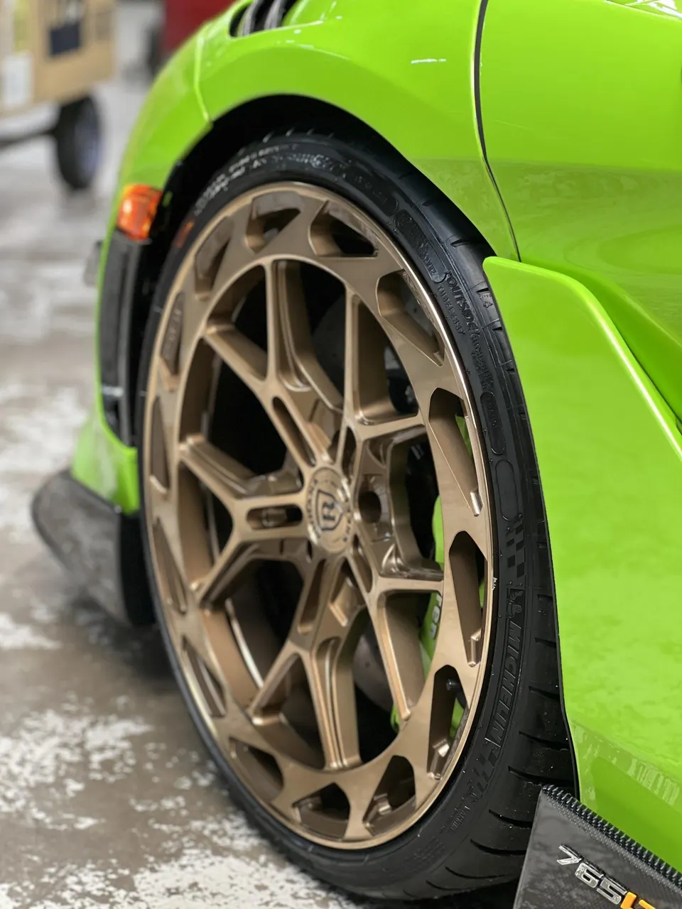 Close-up of a lime green car's bronze custom wheel with Michelin tire and brake caliper.