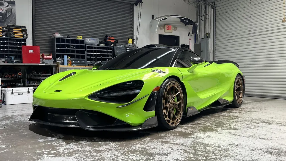 Lime green McLaren 720S with custom bronze wheels and carbon fiber aero parked inside a performance tuning shop.