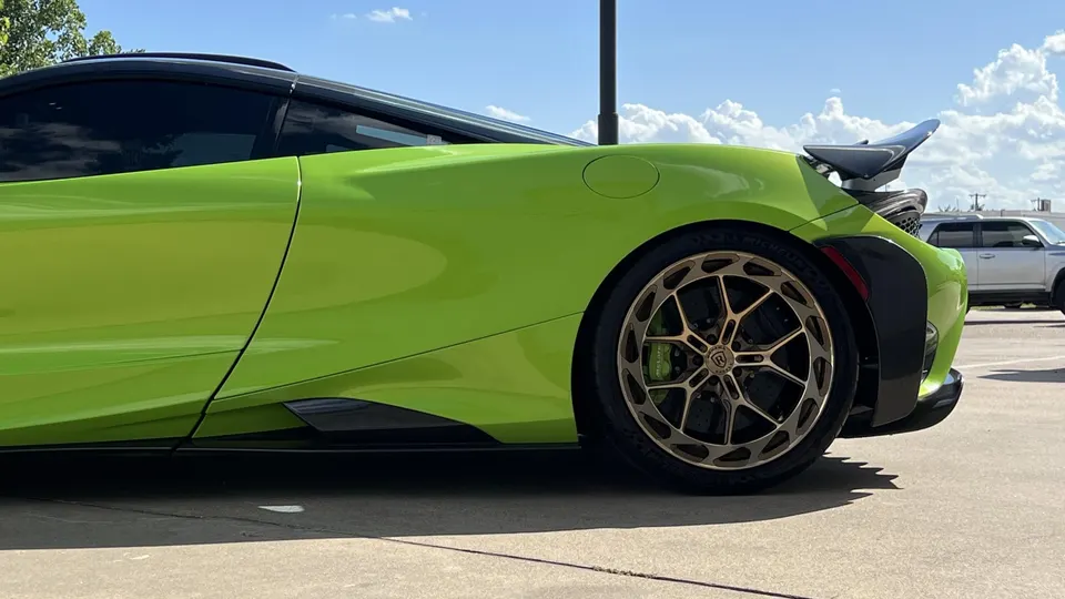 Side view of a lime green McLaren supercar featuring custom multi-spoke wheels, a large rear wing, and carbon fiber body accents.