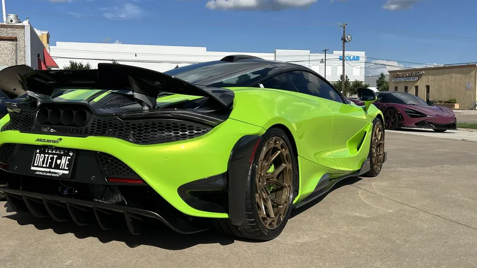 Lime green McLaren supercar with a large carbon fiber wing, rear diffuser, and custom bronze wheels parked outdoors.