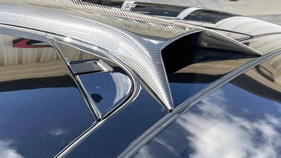 Close-up of a carbon fiber roof scoop on a black performance car, showcasing exterior aerodynamic detail.