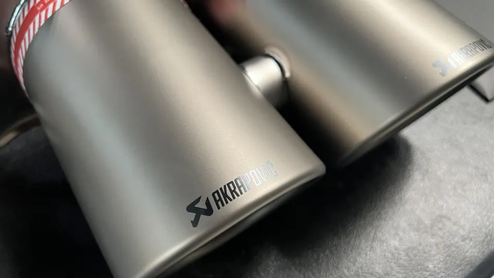 Close-up of Akrapovic titanium exhaust tips, showcasing the brand logo and finish.