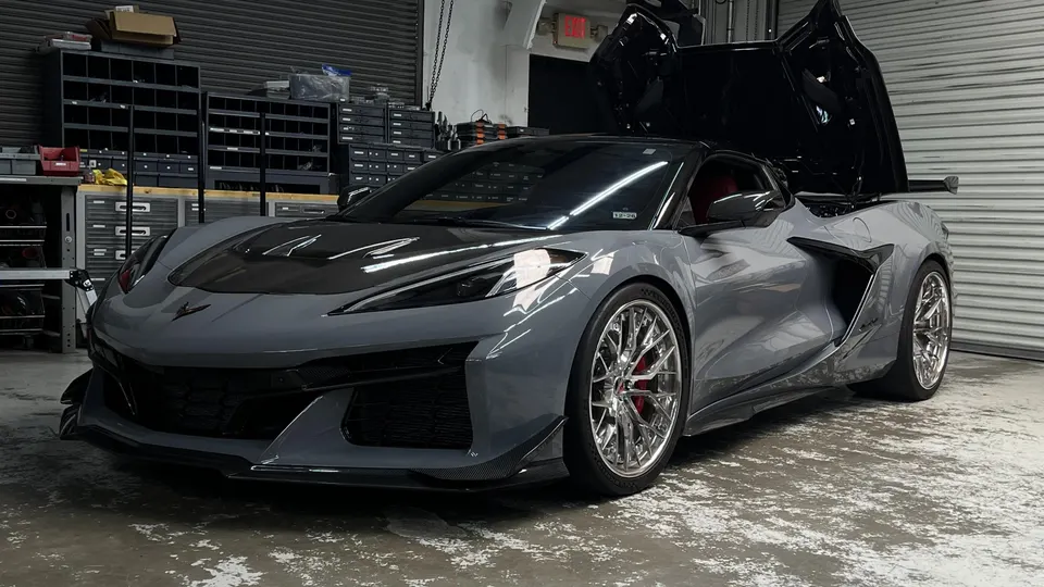 Grey Chevrolet Corvette C8 Z06 with custom chrome wheels and carbon fiber accents parked in a performance shop.