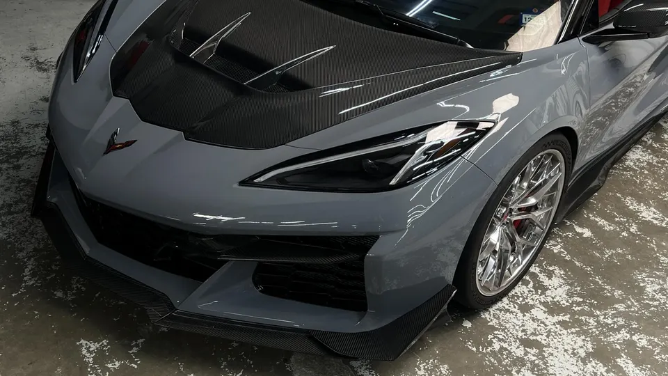 Close-up of a grey Corvette C8 Z06 featuring a carbon fiber hood, front splitter, and custom chrome wheels.