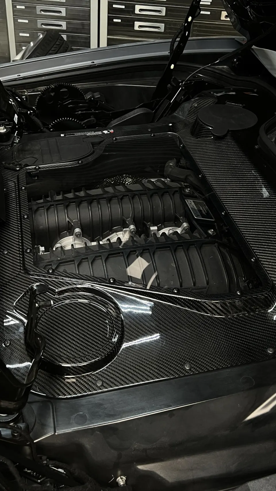 Close-up view of a Corvette C8 engine bay with the intake manifold visible and carbon fiber trim.