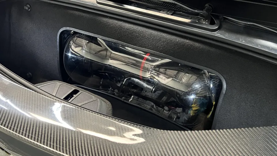 Close-up of a carbon fiber intake system in a high-performance car's engine bay.