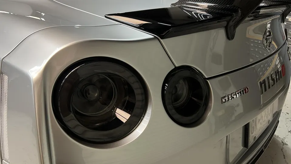 Rear view of a silver Nissan GT-R R35 with blacked-out taillights and a carbon fiber Nismo spoiler.