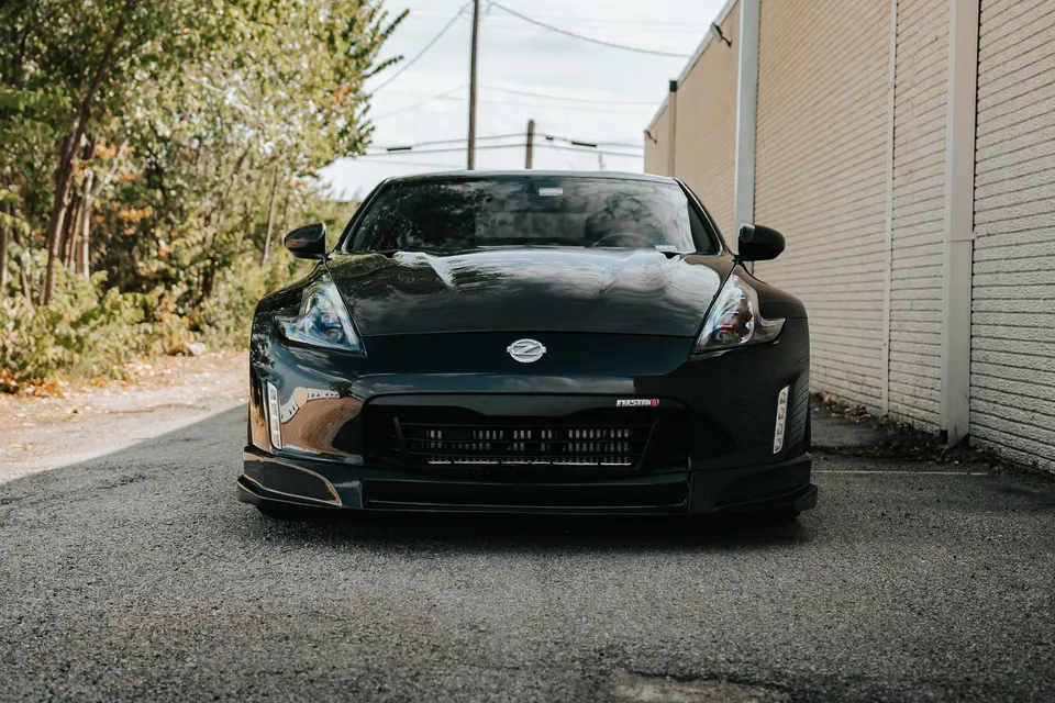 Black Nissan 370Z Nismo parked outdoors, showcasing its front bumper, grille, and headlights.