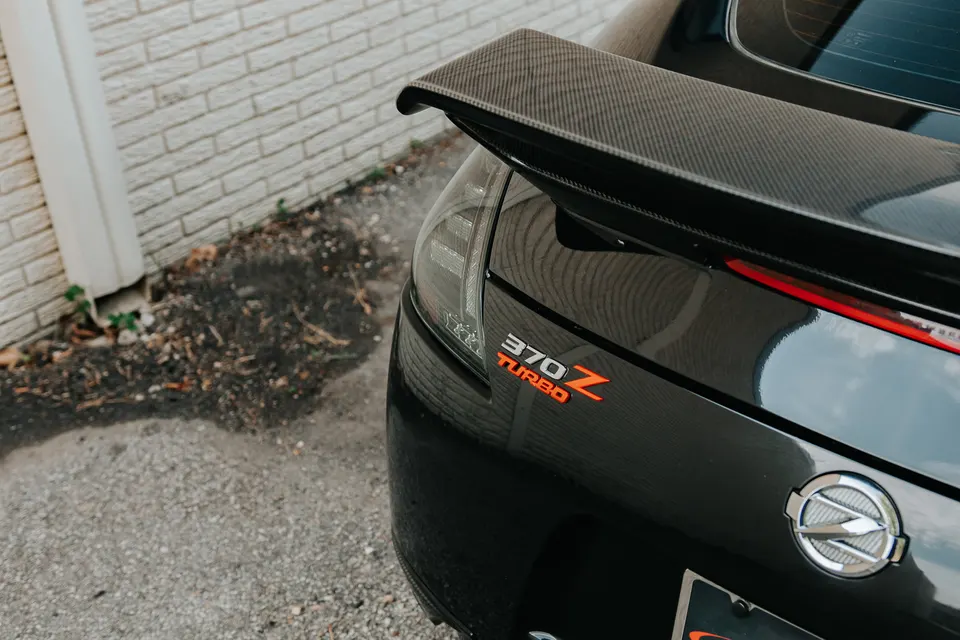 Rear view of a black Nissan 370Z featuring a carbon fiber spoiler and '370Z TURBO' badging.