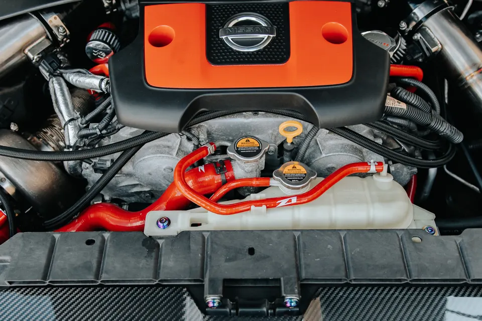 Close-up view of a Nissan engine bay featuring custom red silicone hoses and aftermarket induction components.