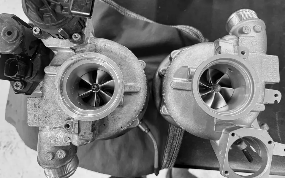 Two performance turbochargers with exposed compressor wheels on a workbench in a tuning shop.