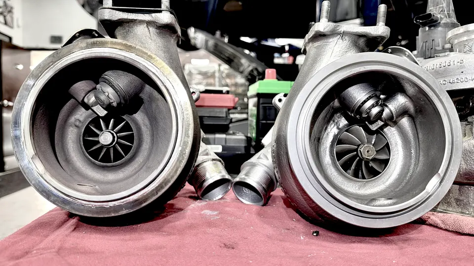 Two new turbochargers on a workbench in a performance tuning shop, ready for installation.