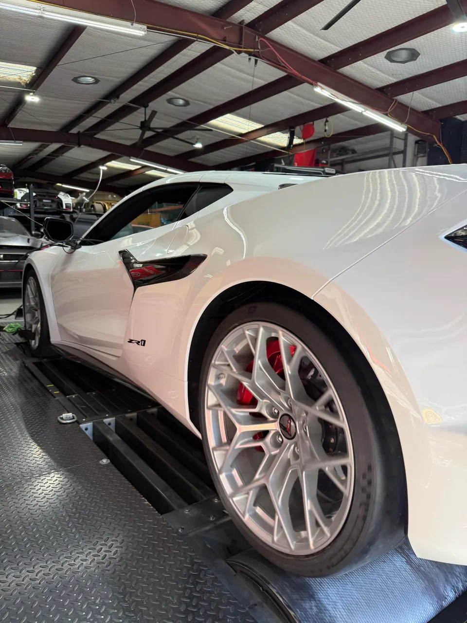 A white C8 Corvette Z06 on a dynamometer at a performance tuning shop.