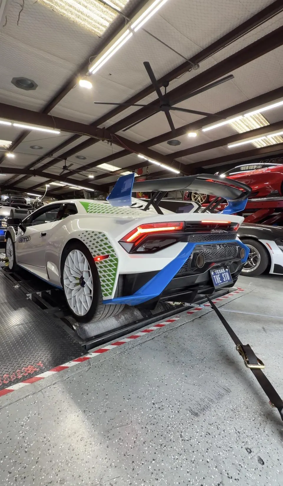 White Lamborghini Huracan STO strapped to a dyno in a performance tuning shop.