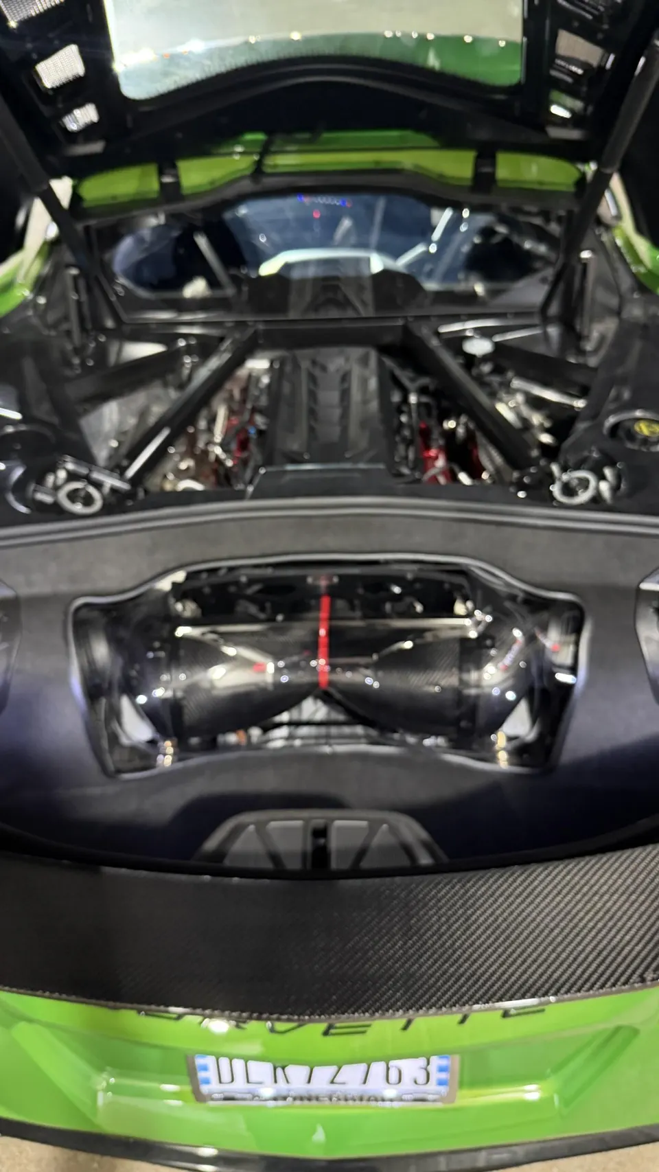 Detailed view of a green C8 Corvette engine bay showcasing a carbon fiber induction system.