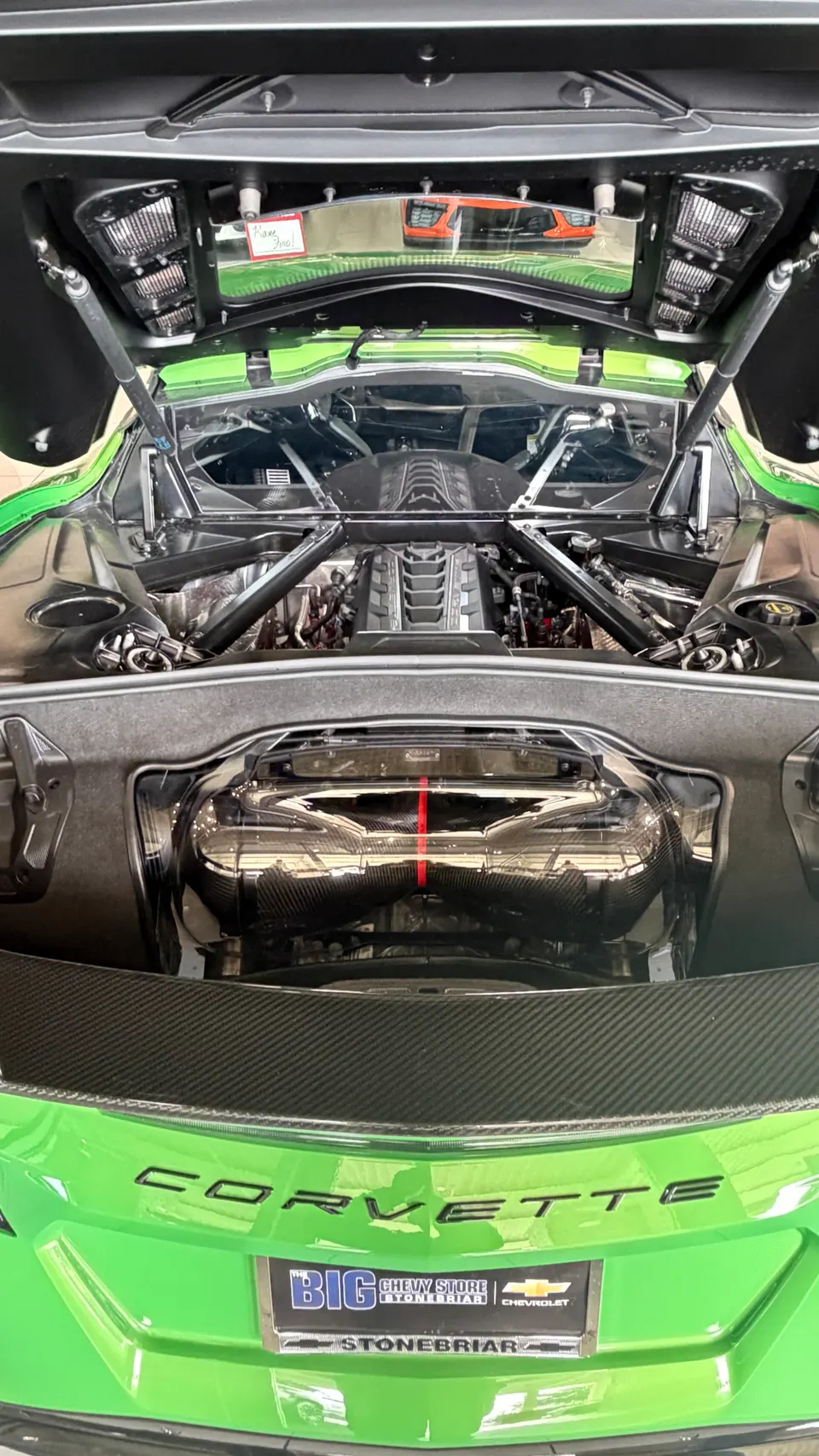 Green Corvette C8 mid-engine bay with carbon fiber induction system and engine visible.