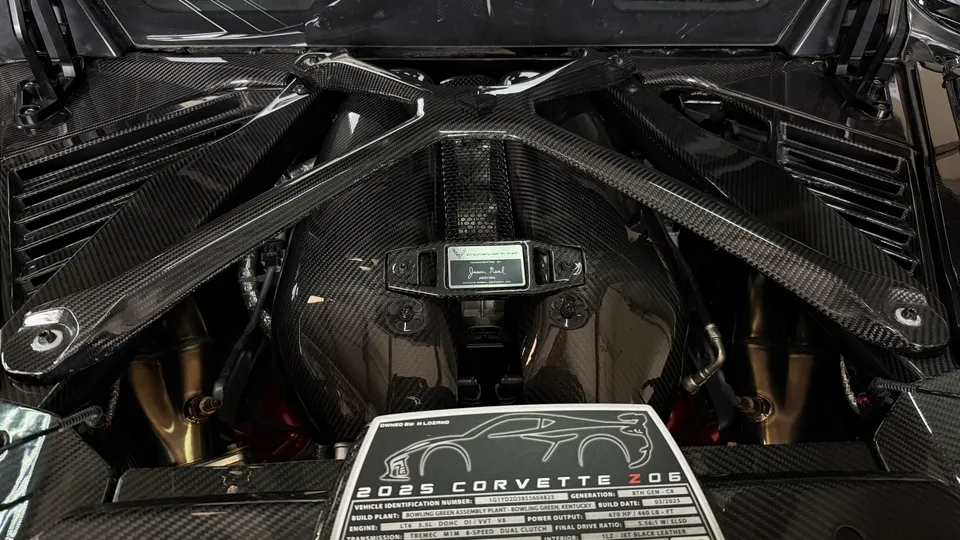 A detailed view of a 2025 Corvette Z06 LT6 engine bay, showcasing carbon fiber components and the intake manifold.
