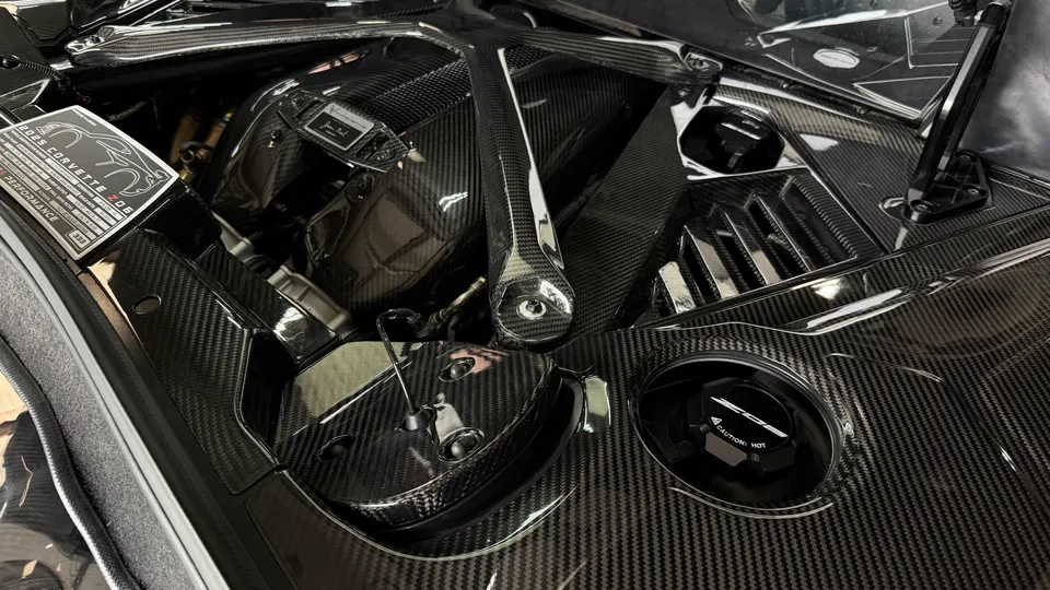 Close-up view of a 2023 Corvette Z06 engine bay featuring extensive carbon fiber components and a strut brace.
