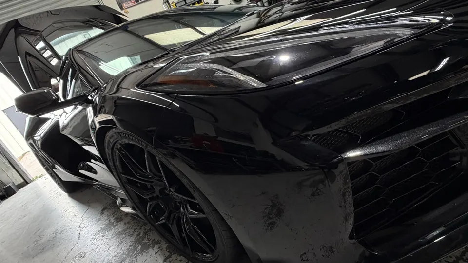 Sleek black McLaren supercar with glossy paint, captured from a dynamic front-side angle in a shop setting.