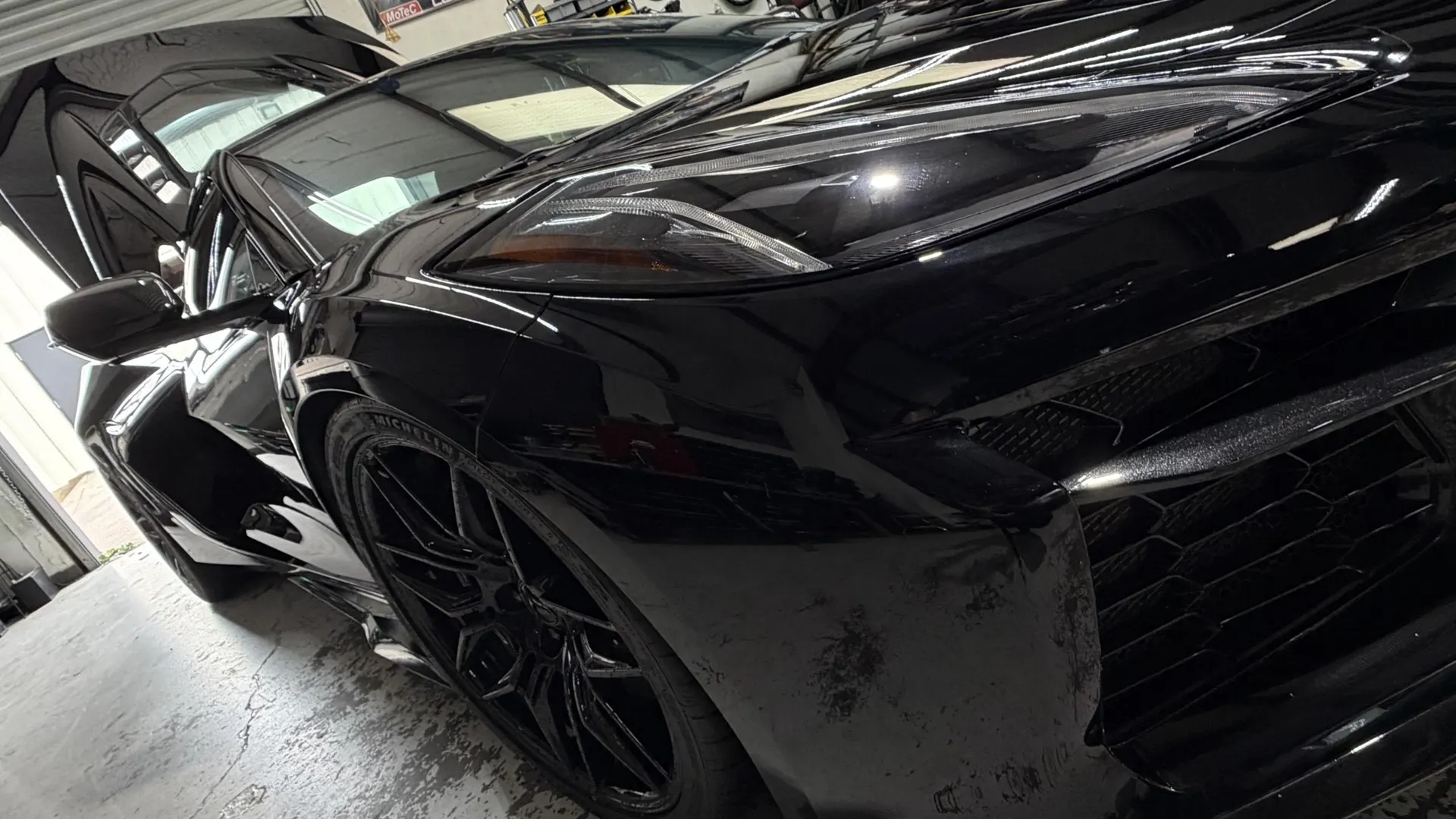 Sleek black McLaren supercar with glossy paint, captured from a dynamic front-side angle in a shop setting.