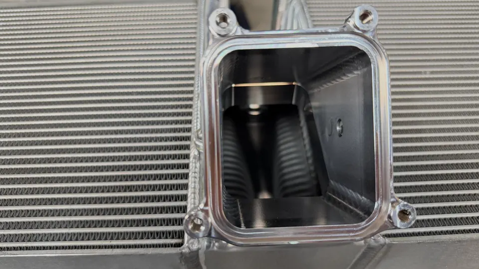 Close-up of an aluminum intercooler core and end tank, showcasing the internal fins and construction of the performance part.