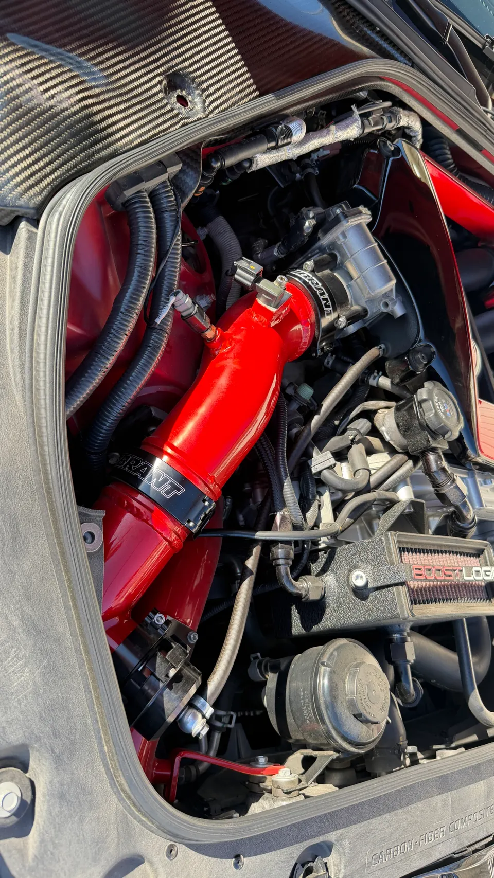 Close-up of a high-performance engine bay featuring a red Vibrant Performance intake system and Boost Logic air filter.