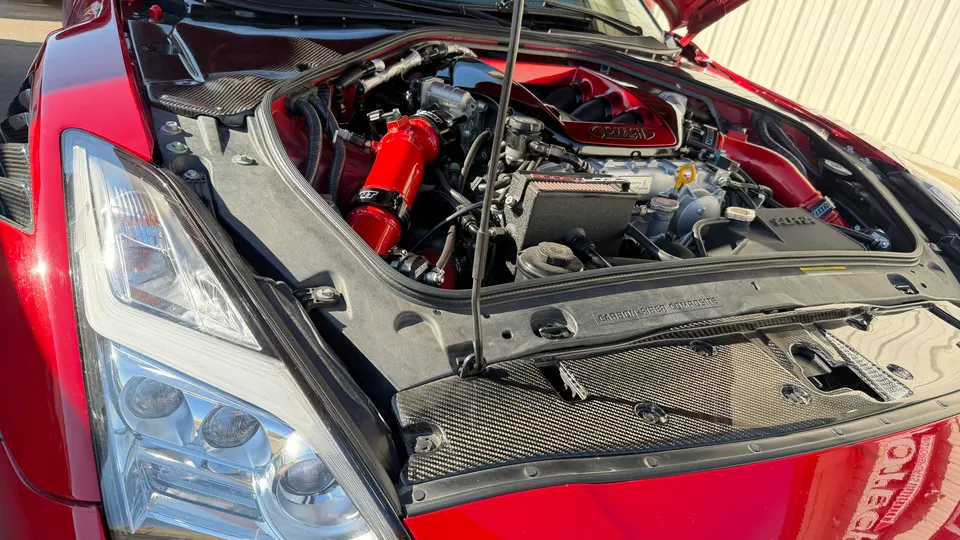 Close-up of a red Nissan GT-R engine bay featuring a performance induction system and carbon fiber accents.