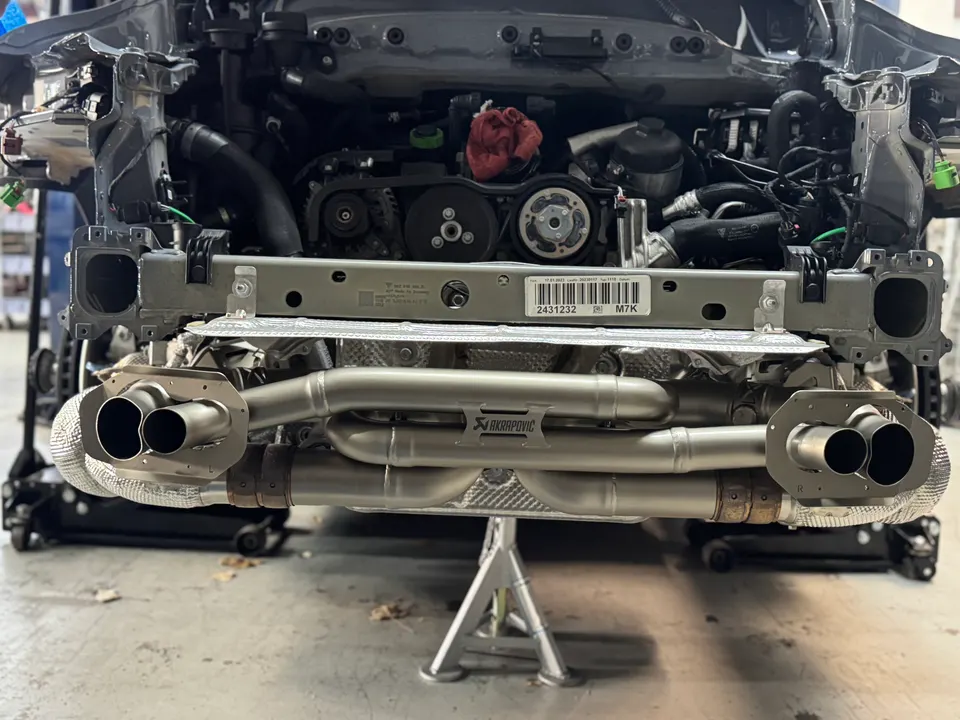 Akrapovic exhaust system installed on the rear of a performance car in a shop environment.