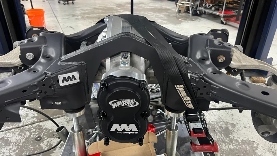 A Winters Motorsports differential and subframe assembly being worked on in a performance shop, secured with SpeedStrap.