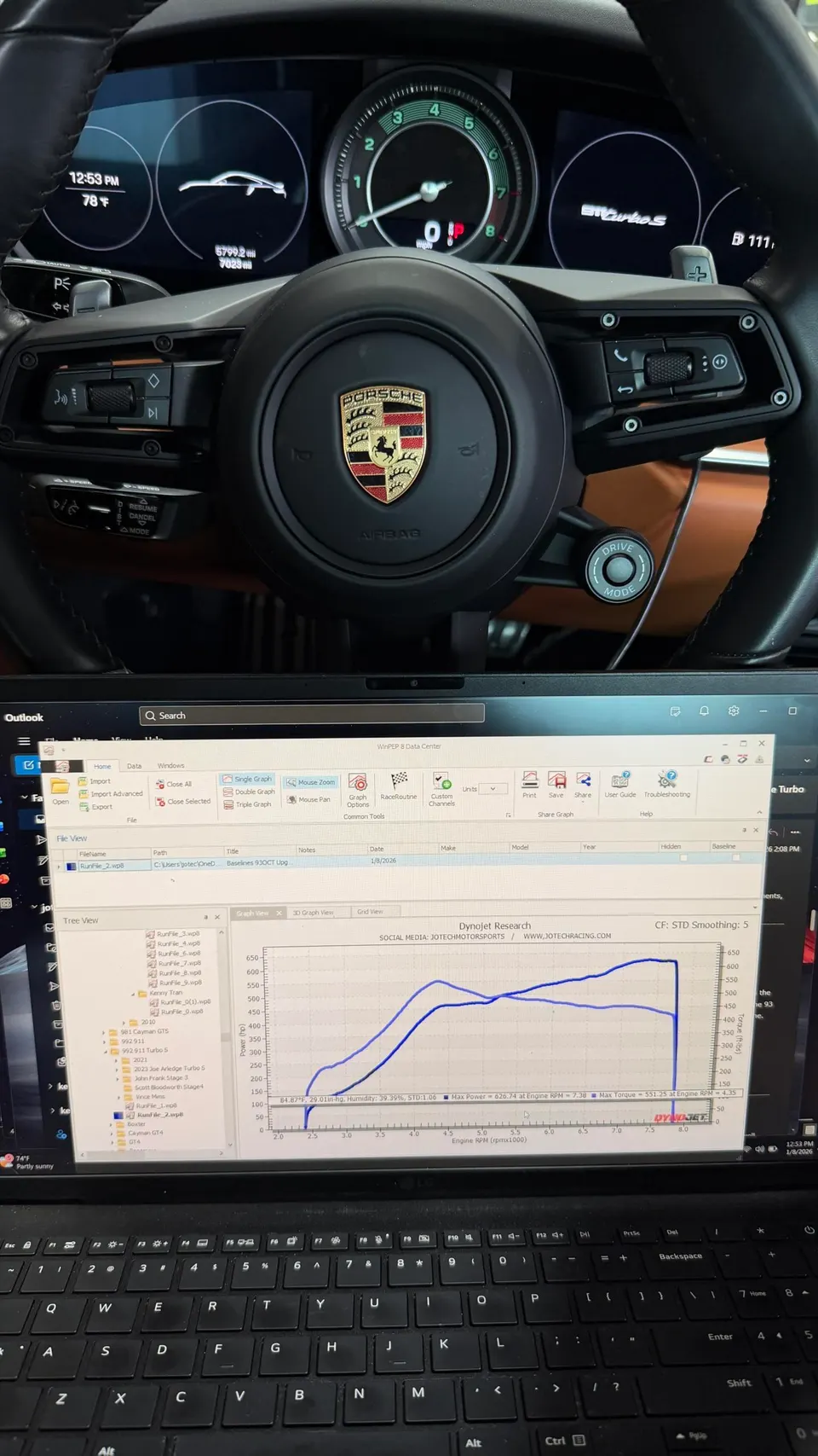 Porsche 911 Turbo S interior with steering wheel and dashboard, alongside a laptop displaying dyno tuning results.