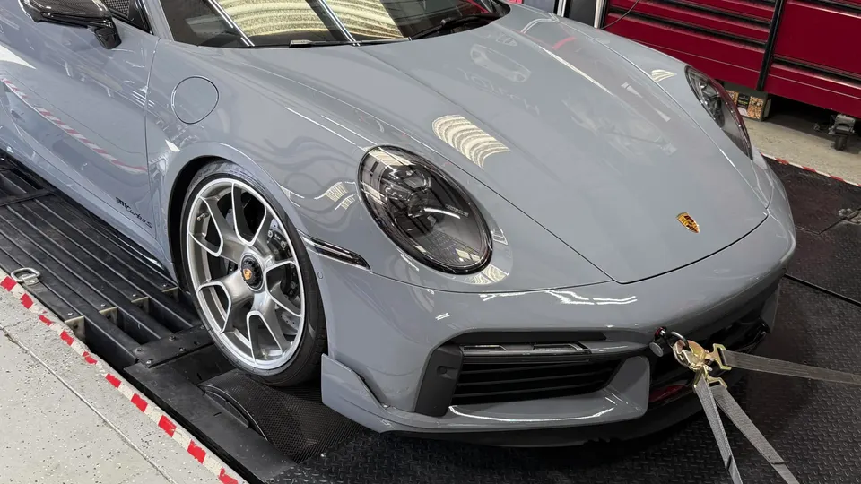 Grey Porsche 911 Turbo S strapped to a dynamometer for performance testing at a tuning shop.