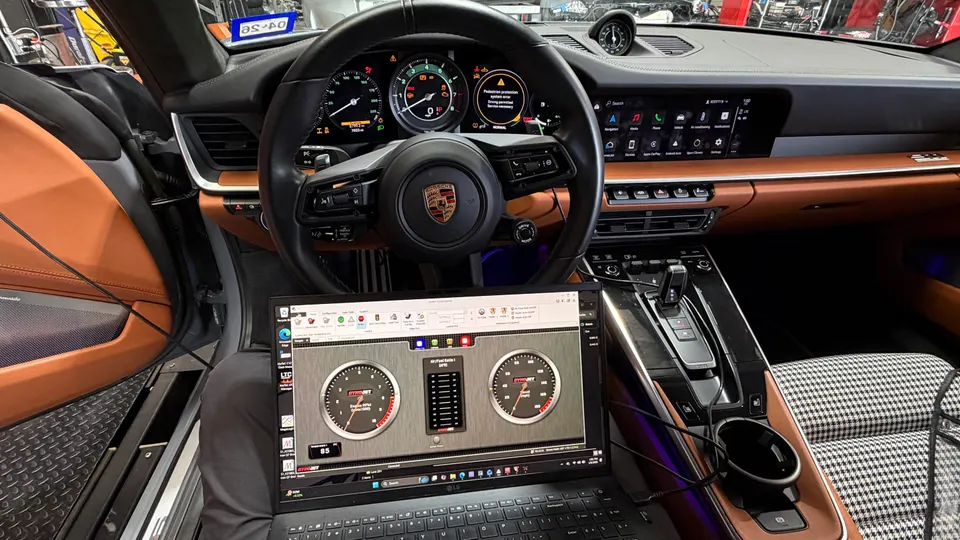 Interior view of a Porsche 911 with a laptop running Dynojet tuning software during a dyno session.