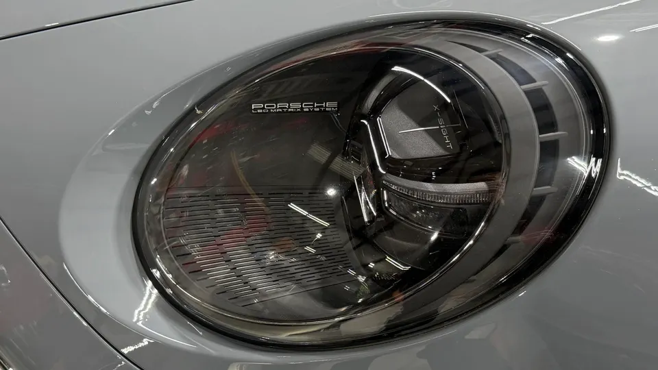 Close-up of a Porsche LED Matrix System headlight on a grey car, highlighting the advanced lighting technology.