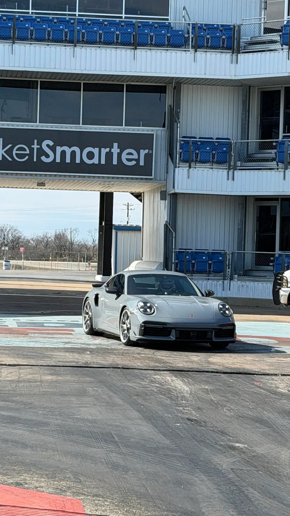 A grey Porsche 911 Turbo S in the staging lane of a drag strip under a TicketSmarter banner.