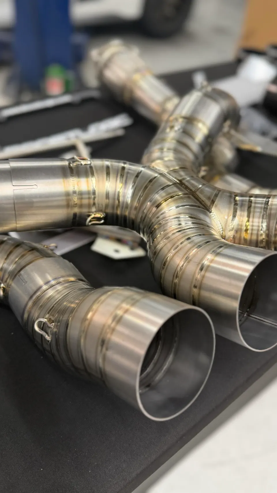 Close-up of a custom titanium exhaust system with intricate welds, showcasing high-performance automotive fabrication.