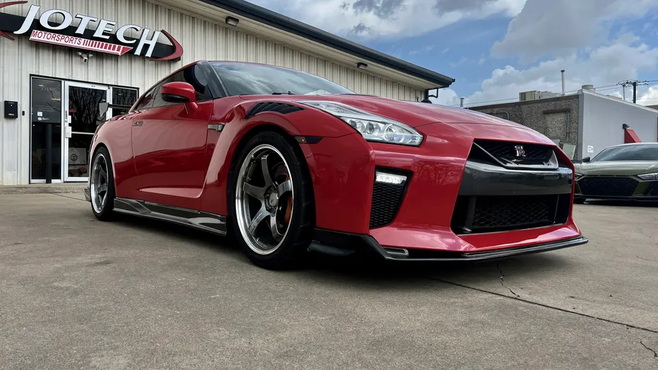 Red Nissan GT-R with custom wheels and carbon fiber aero parked outside Jotech Motorsports performance shop