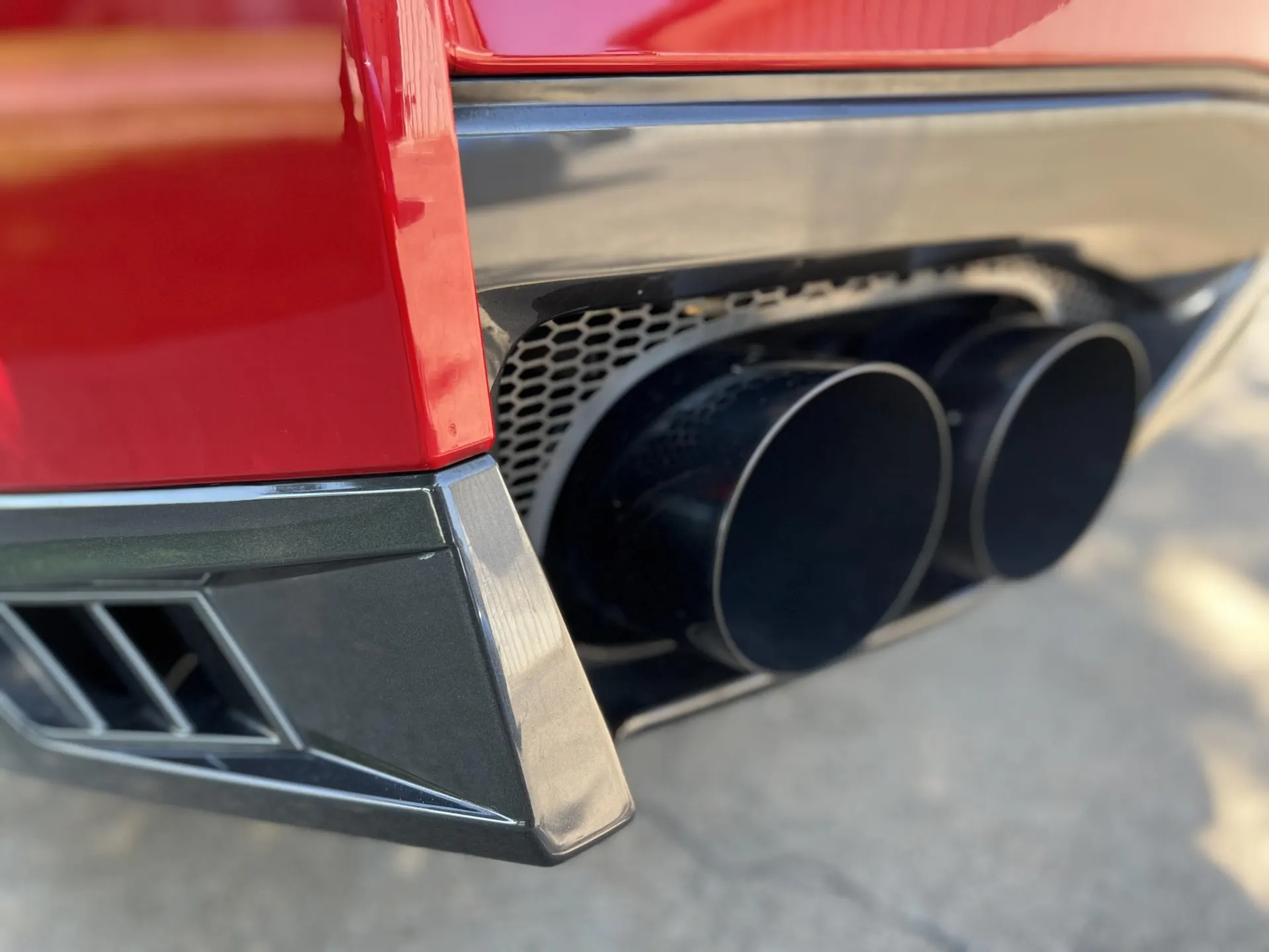 Close-up of a red car's black exhaust tips and rear diffuser.