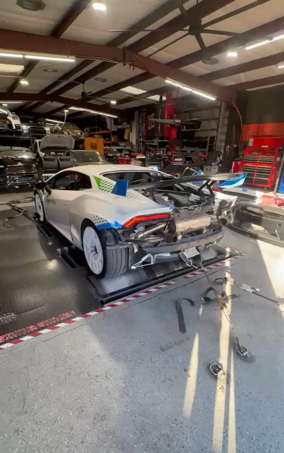 A white Lamborghini Huracan STO on a dyno with its rear bumper removed, showcasing the exhaust system during tuning.