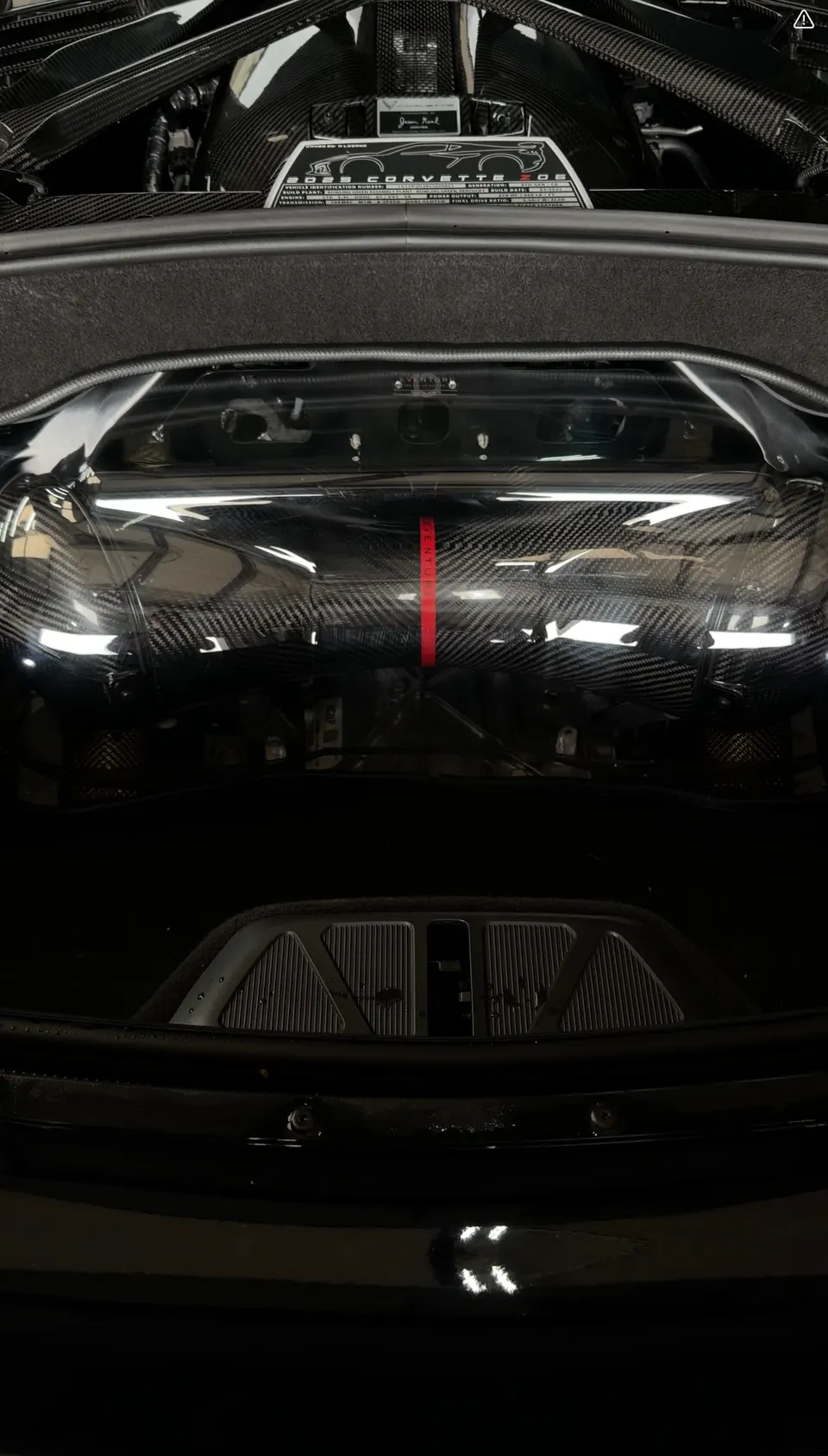 Close-up view of a 2023 Corvette Z06 engine bay with carbon fiber engine cover and build plaque.