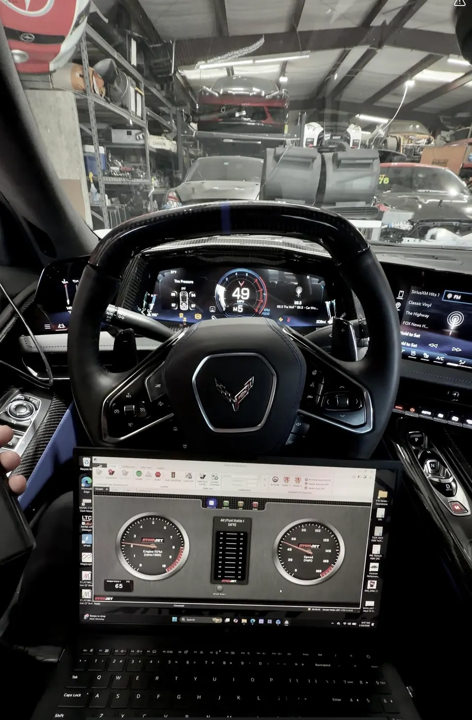 Interior view of a Corvette C8 with a laptop displaying Dynojet tuning software in a performance shop.