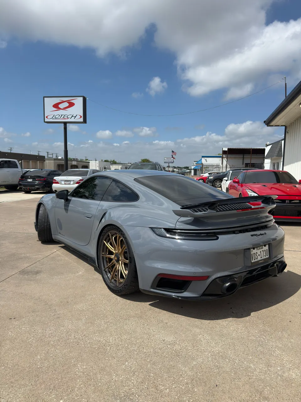 Grey Porsche 911 Turbo S with gold aftermarket wheels parked outside Jotech Motorsports shop.