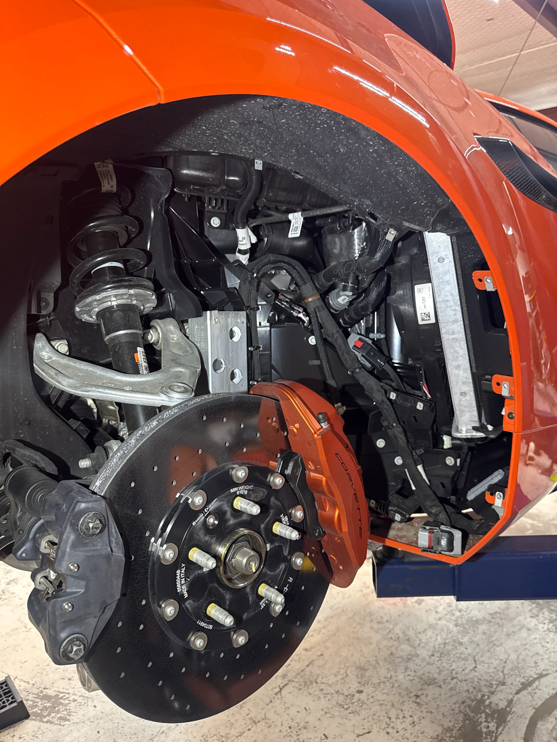 Your Corvette is on the lift, showing the front suspension, large rotor, and orange caliper.