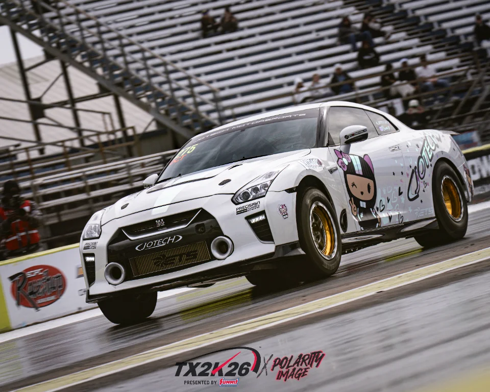 A white Nissan GT-R R35 drag car with Jotech Motorsports livery on a drag strip, with grandstands in the background.