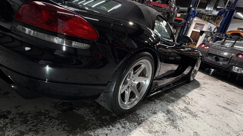 Black Dodge Viper with performance wheels parked in a shop, with a grey Nissan GT-R and car lifts in the background.