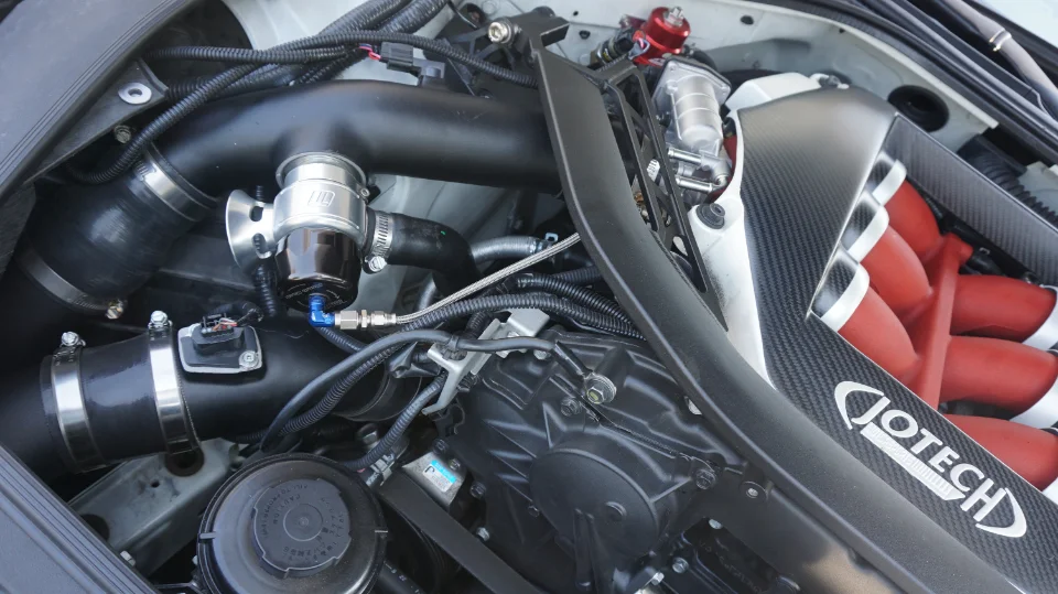 Close-up of a Jotech Motorsports tuned engine bay featuring a carbon fiber intake manifold cover and performance induction components.