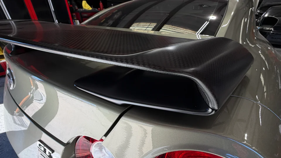 Close-up of a Nissan GT-R's carbon fiber rear wing and trunk, showcasing exterior aerodynamic modifications.