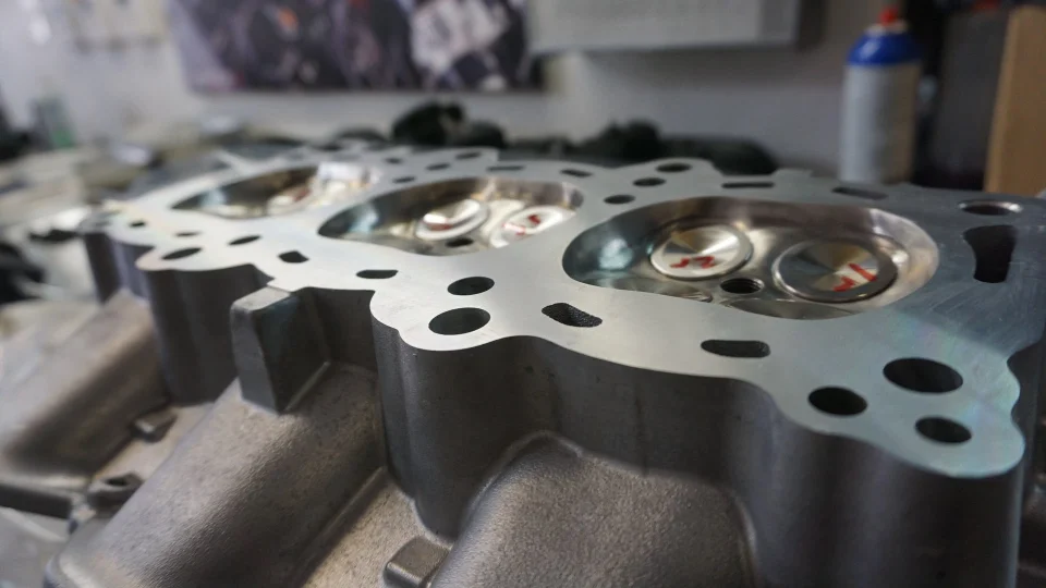 Close-up of a performance engine cylinder head with visible valves, ready for assembly.