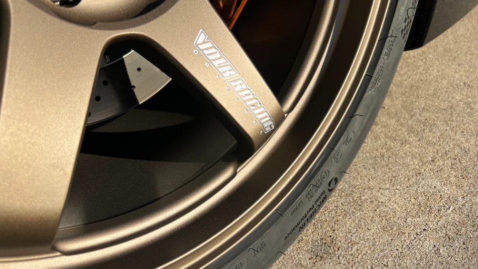 Close-up of a bronze Volk Racing wheel with a Michelin tire and perforated brake rotor.