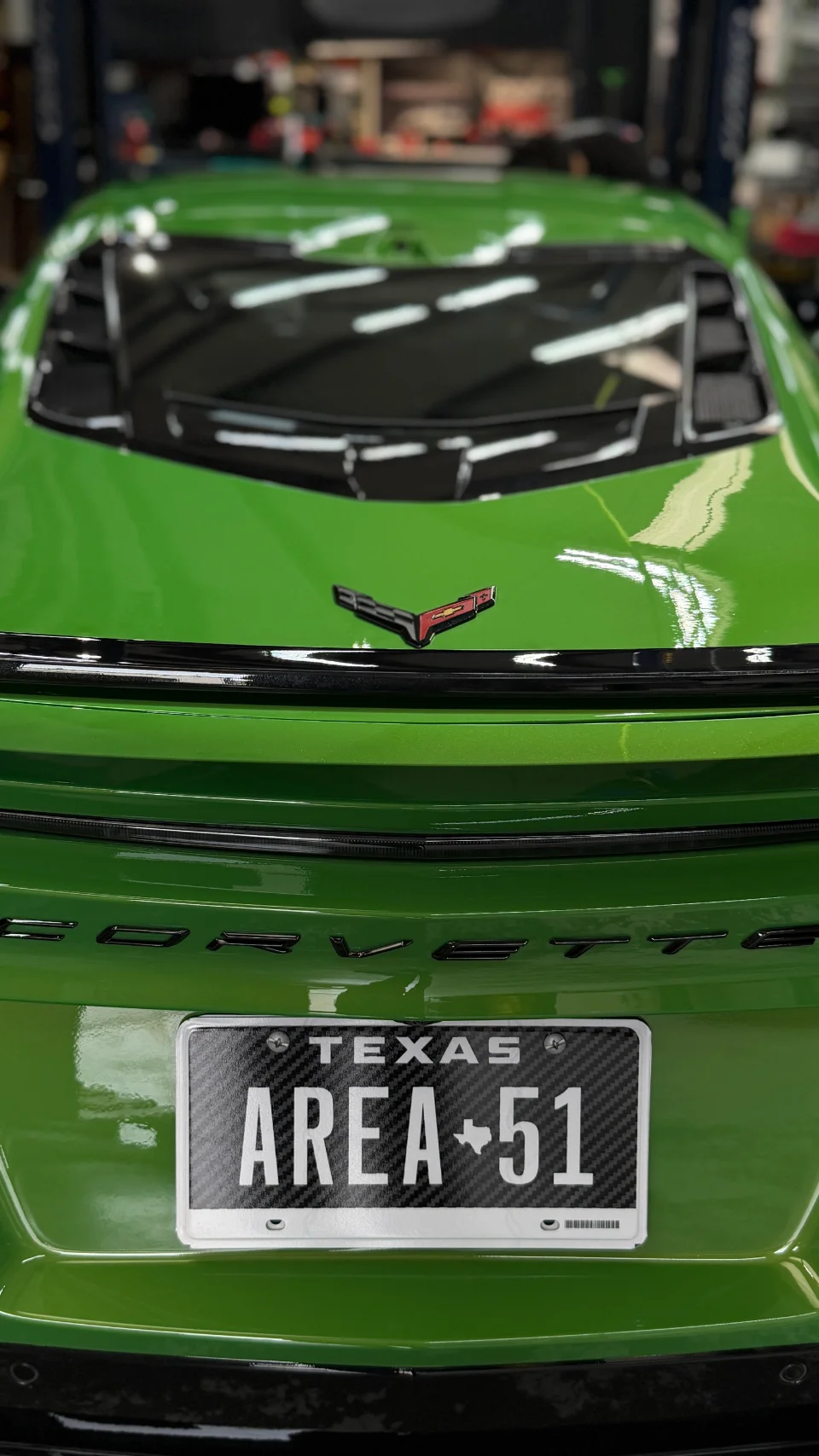 Rear view of a bright green Chevrolet Corvette C8 with a custom Texas 'AREA 51' license plate.