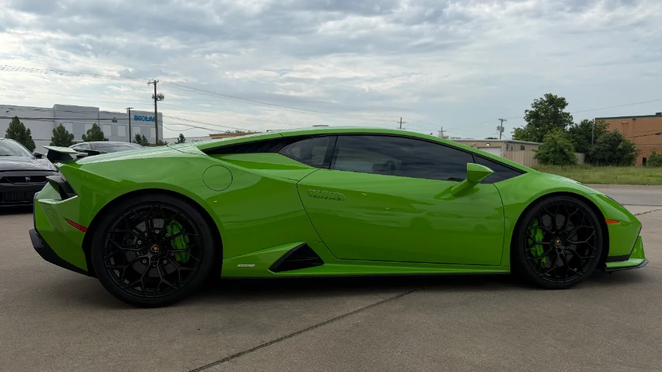 A bright green Lamborghini Huracan with black wheels and green brake calipers parked outdoors on a cloudy day.
